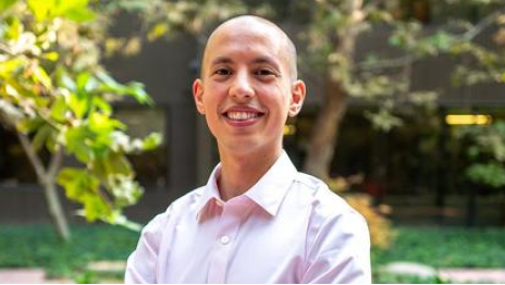 Yassine in a pink button-up shirt, smiling