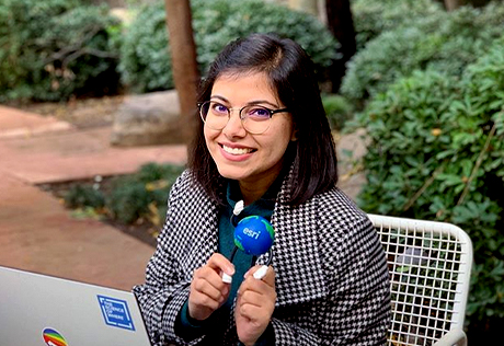 Woman with her laptop and Esri merchandise, sitting at a table on the Redlands campus