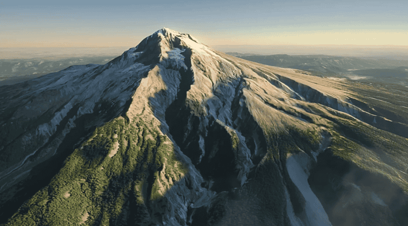 Aerial view of a snow-capped mountain with green slopes