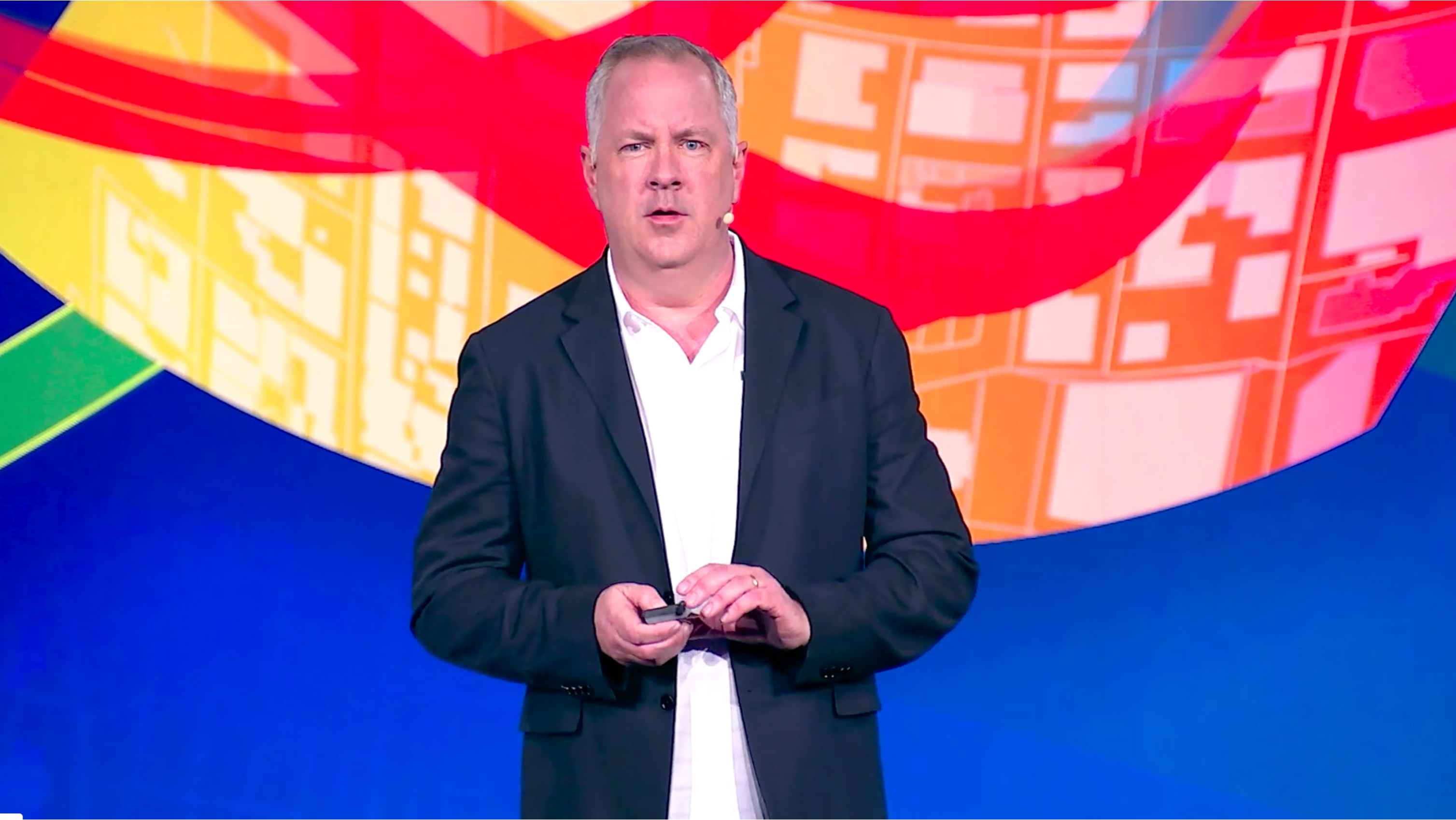 A man in a suit standing in front of a colorful background
