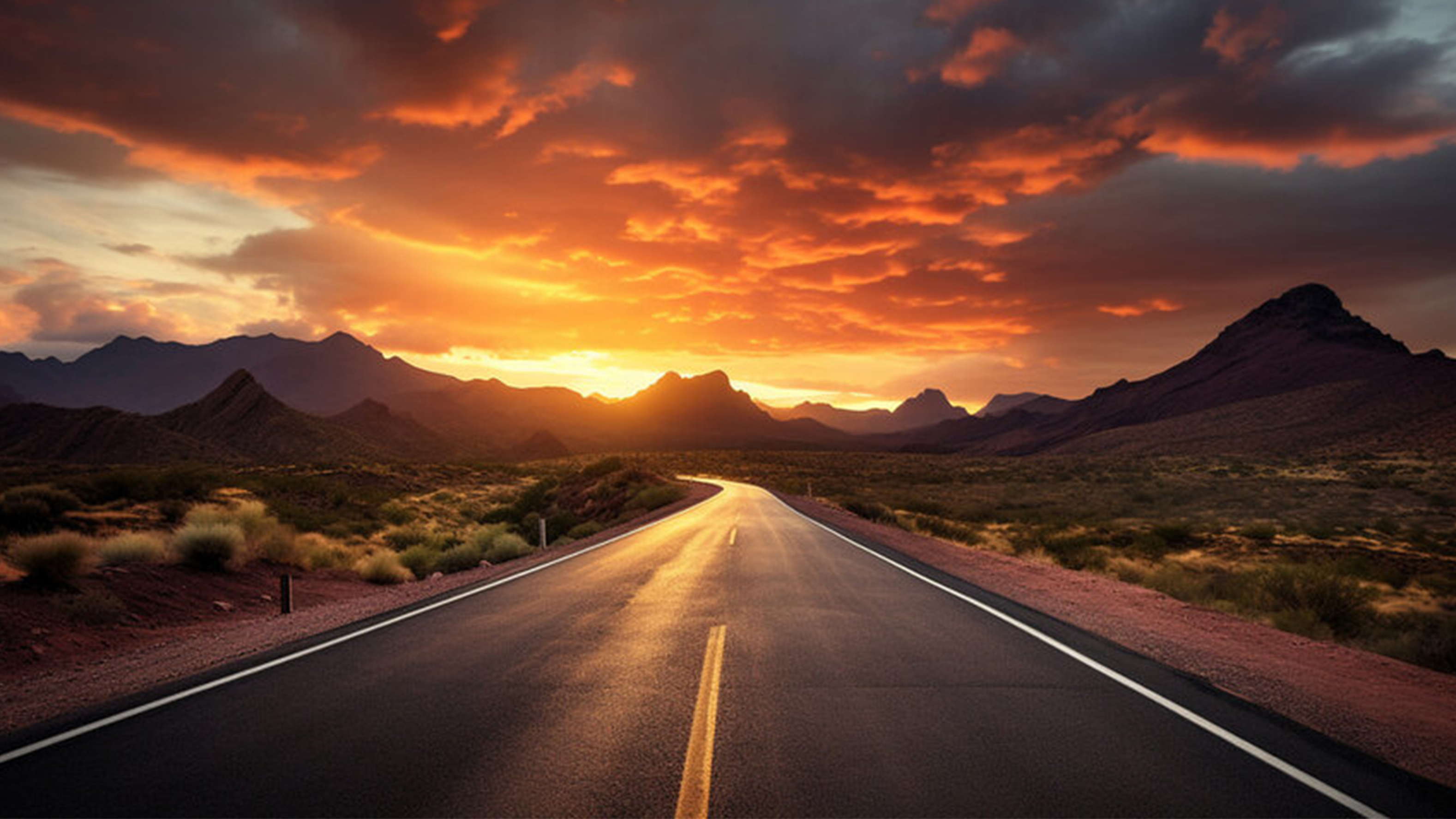 A two-lane road in a barren desert landscape as the sun sets over mountains in the distance