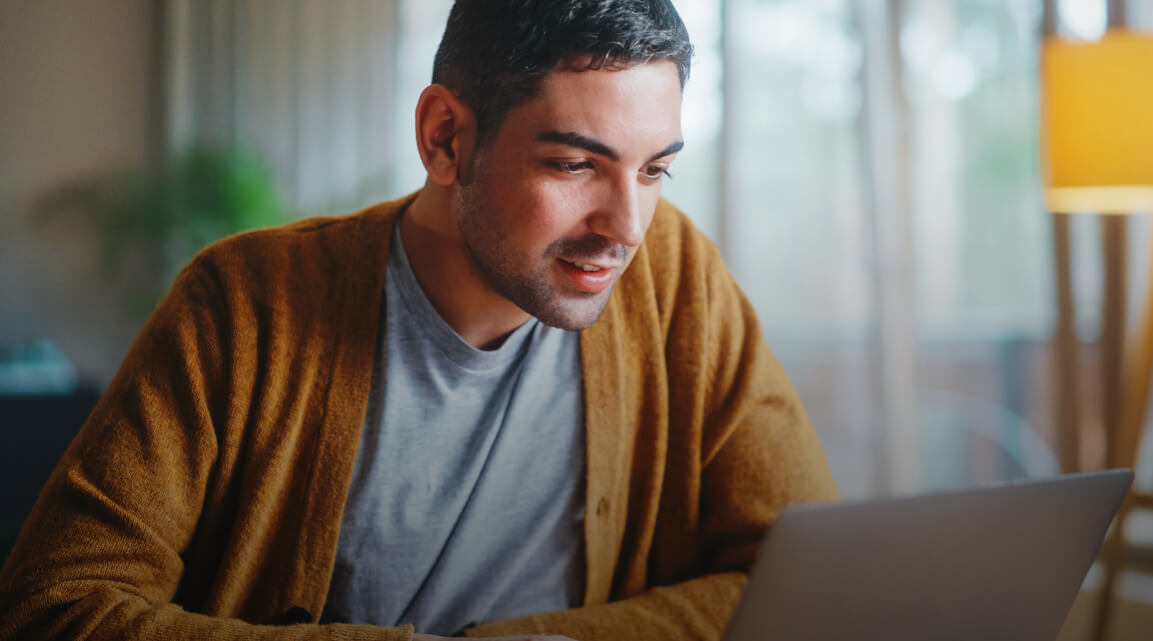 A person sitting at a desk and looking at a laptop computer