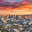 Aerial view of Phoenix, Arizona at sunset, illuminated by warm, orange light against a vibrant sky.