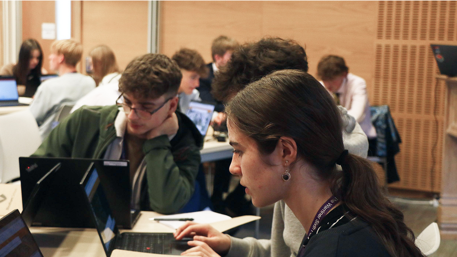 Students sitting at a table working together on their own laptops