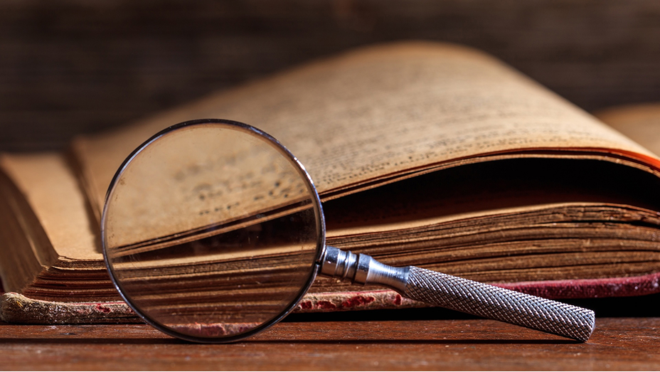 A looking glass propped on its side in front of an old book