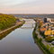 An aerial view of Wheeling, West Virginia, at sunset, with the Ohio River, a bridge, and the city's buildings and streets