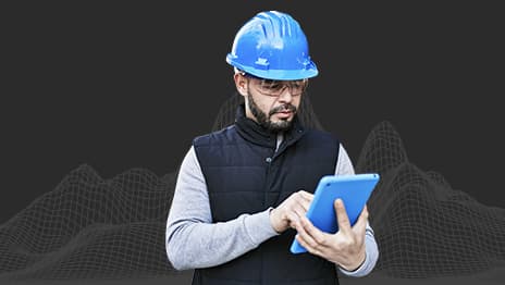A person wearing a blue hard hat and safety glasses using a tablet overlaid on a wireframe of a mountain range