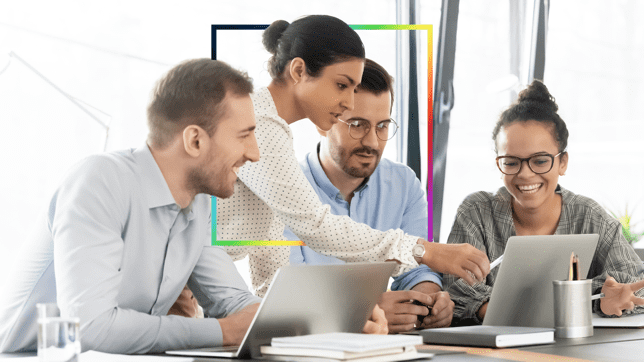 A consultant partnering with three office workers, showing them information on laptops